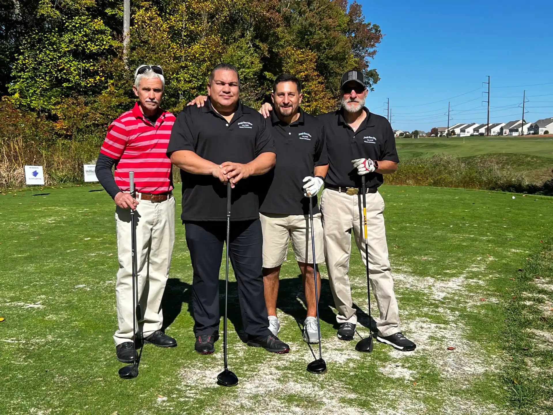 A group of people holding golf sticks in hand with trees in the back